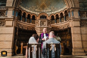 A serene wedding ceremony at Friedhofskirche in Wuppertal, Germany, captured from behind the couple as the priest officiates at the ornate altar. 
